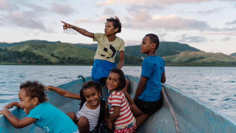 Children from VuniSaviSavi, Fiji, sit in the village boat as they travel to their favorite swimming spot, a deep hole in the coral reef called 'The Tomb', not far from shore. Photo: Alana Holmberg/World Bank