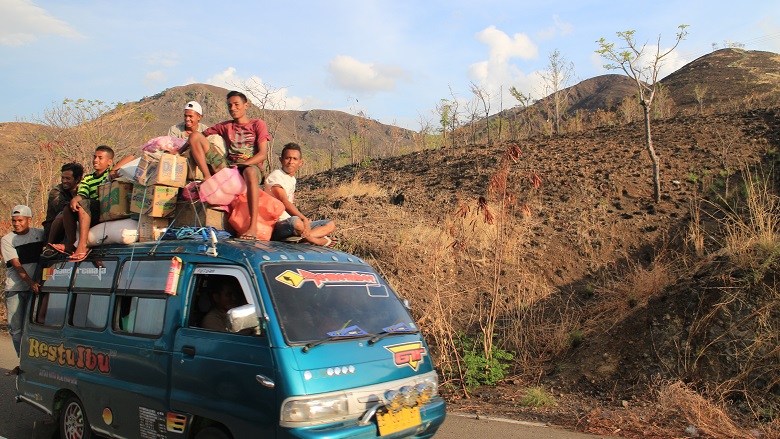 Young men riding on top of a van in Indonesia